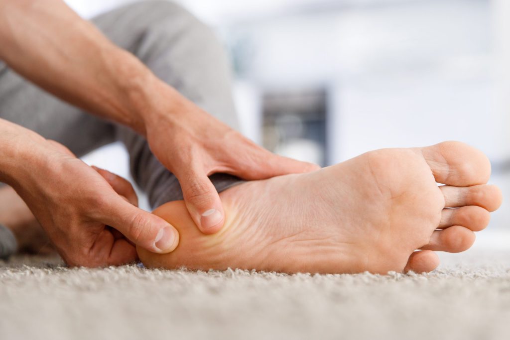 patient with Diabetic neuropathy hands giving foot massage to himself after a long walk, suffering from pain in heel