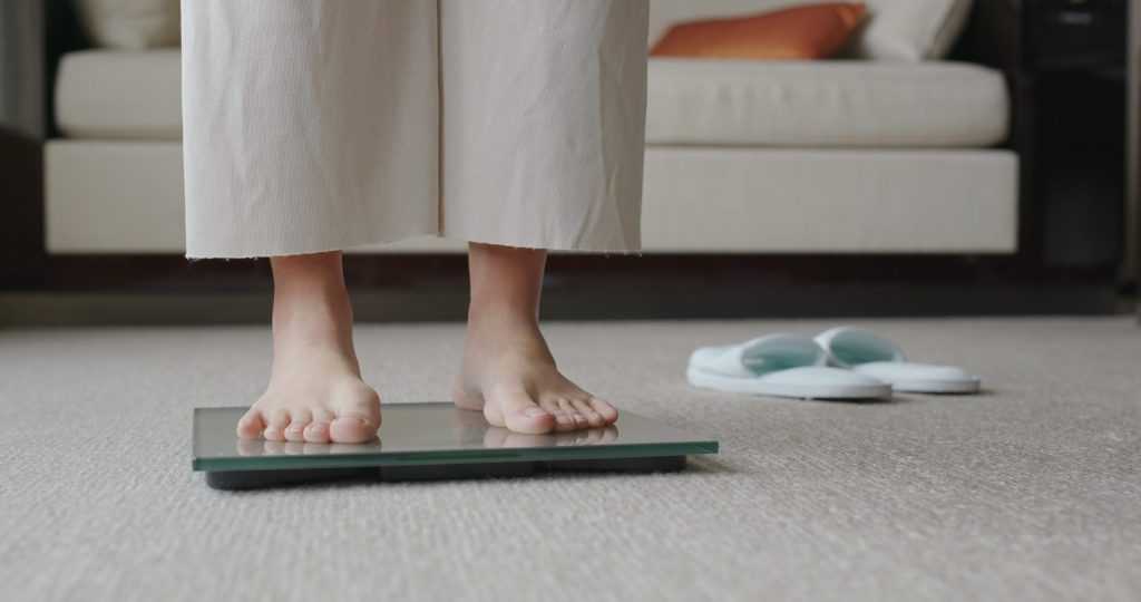 Close up on Woman feet on scale to measure her weight. Obesity and foot problems concept