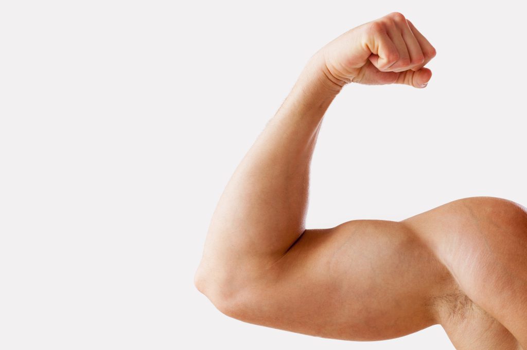 Close-up of muscular man showing his bicep while standing against grey background. Healthy bones concept