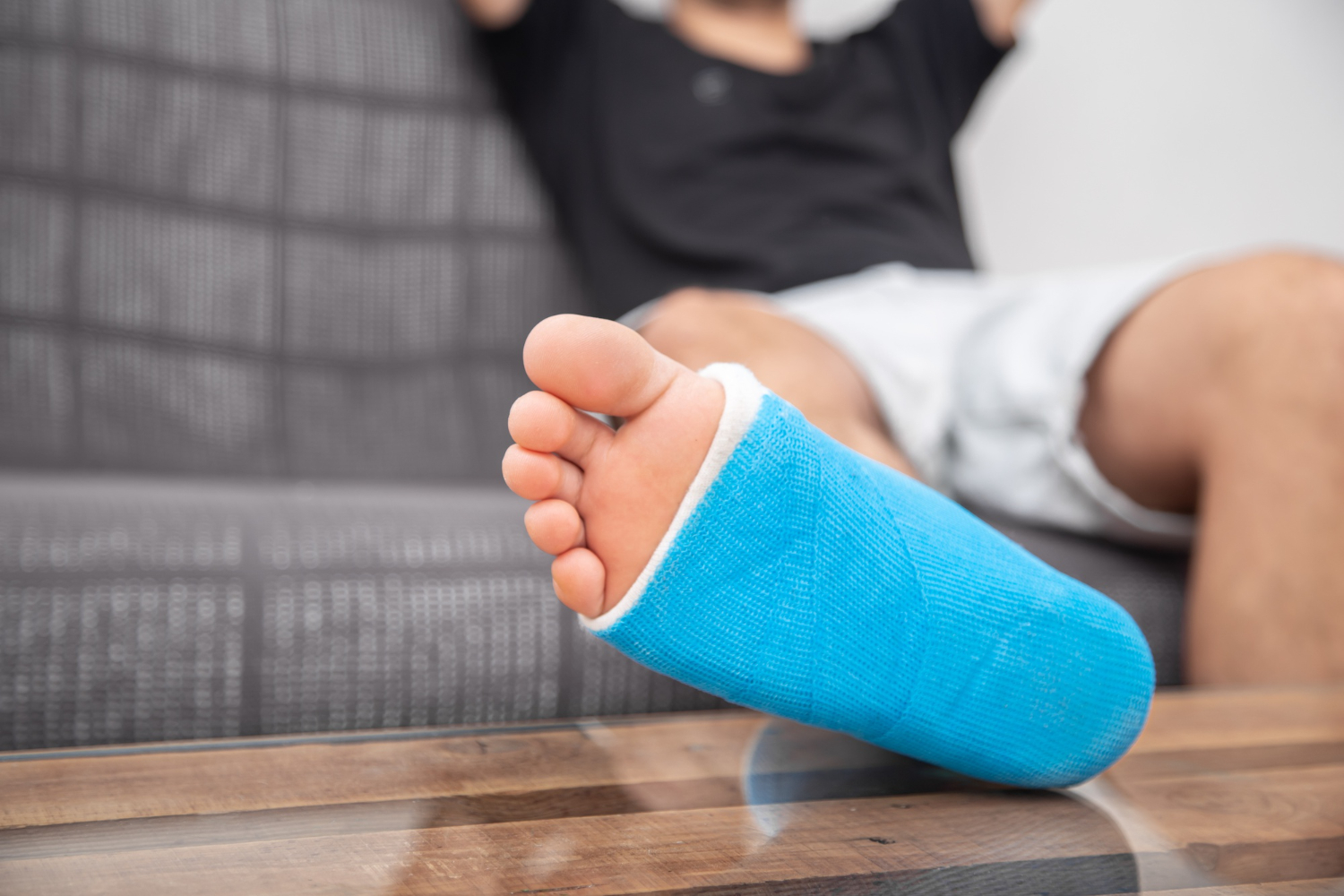 Close up of man with broken leg in cast on couch at home. sports injury concept. Leg cast and toes after injury fracture, dislocation, sprain. Human healthcare and medicine concept. Fractures and sprains.