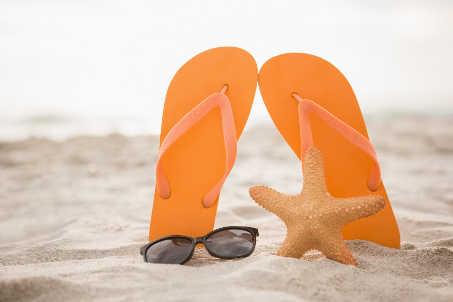 Photo flip flop, sunglasses and starfish in sand. Summer, beach.