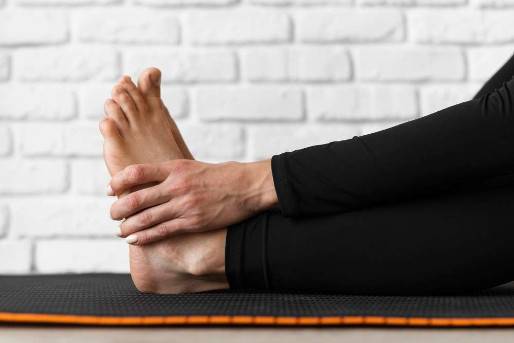 Close-up hands holding feet. Stretching to improve Foot flexibility concept. Girl wearing black pants exercising.