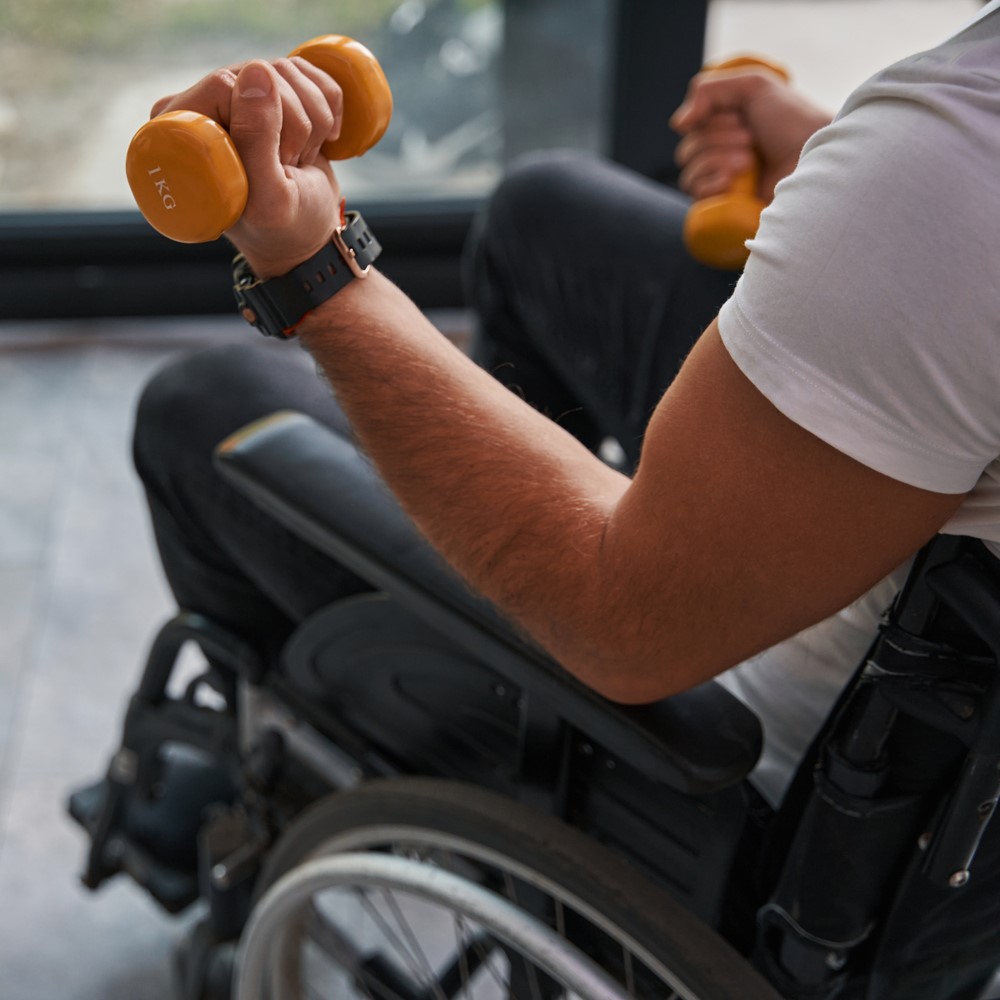 Man with physical disability using a wheelchair holding sports equipment in hand