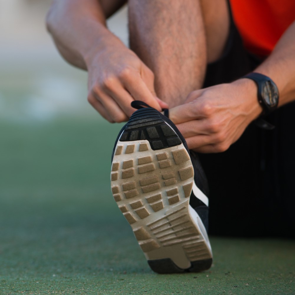 Close-up of male hands tying up sport shoes. Athlete’s foot concept.