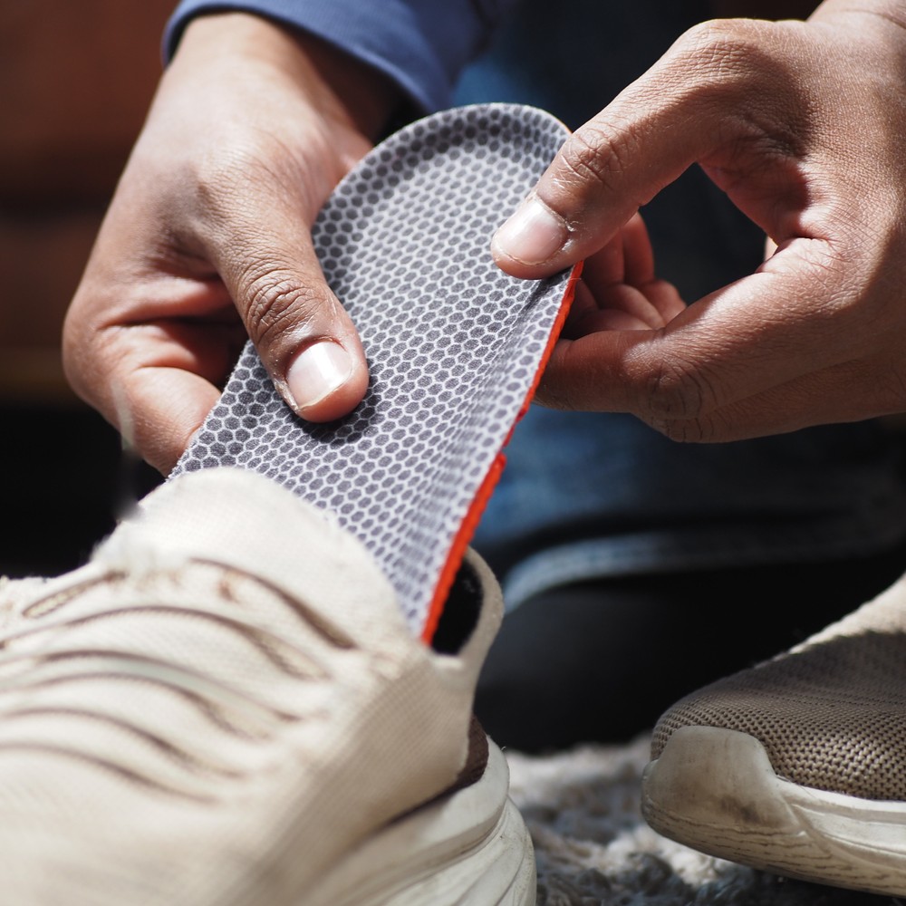 men hand putting Orthopedic insoles in shoes. custom orthotics for flat feet
